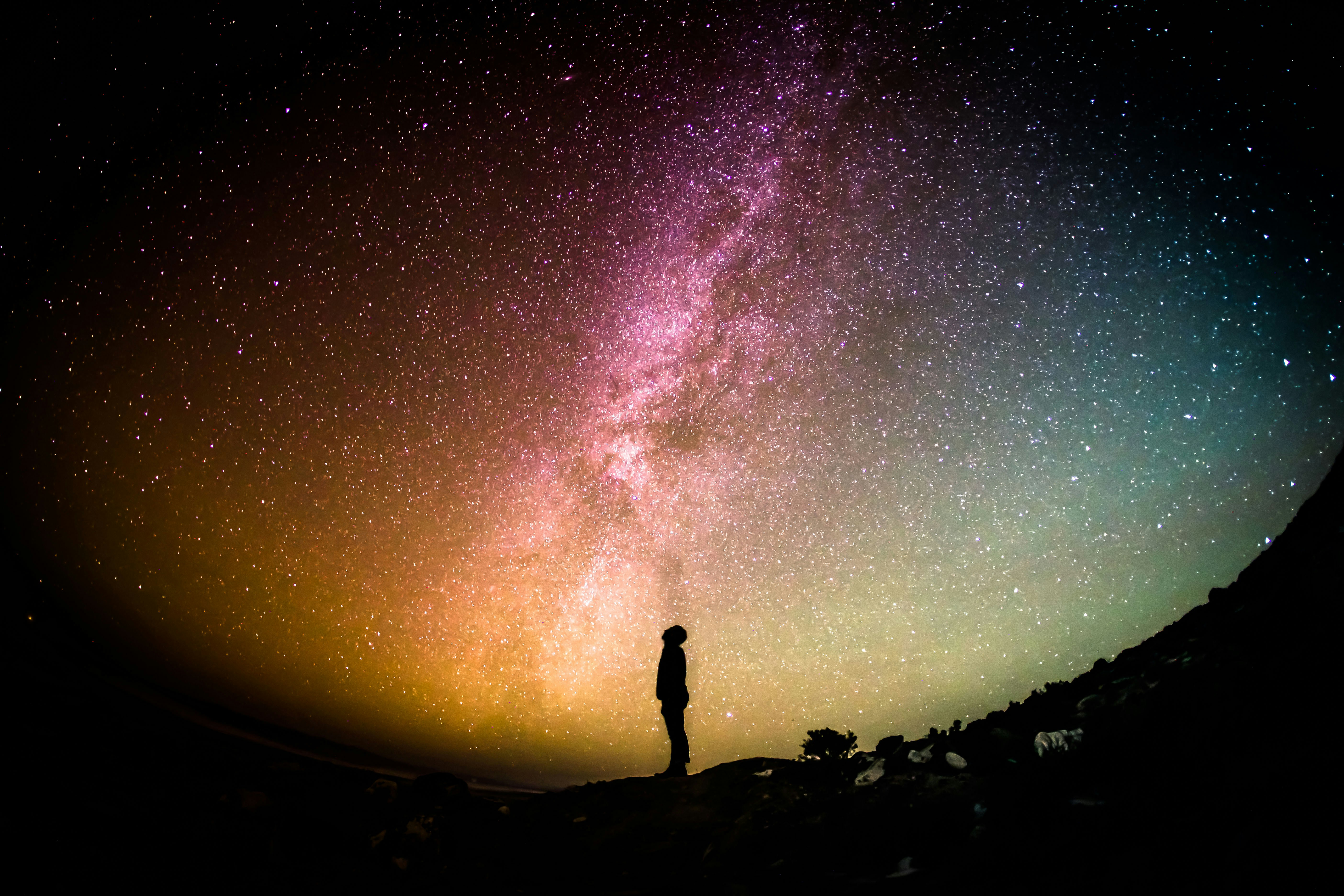 A stargazer beneath a colorful Milky Way