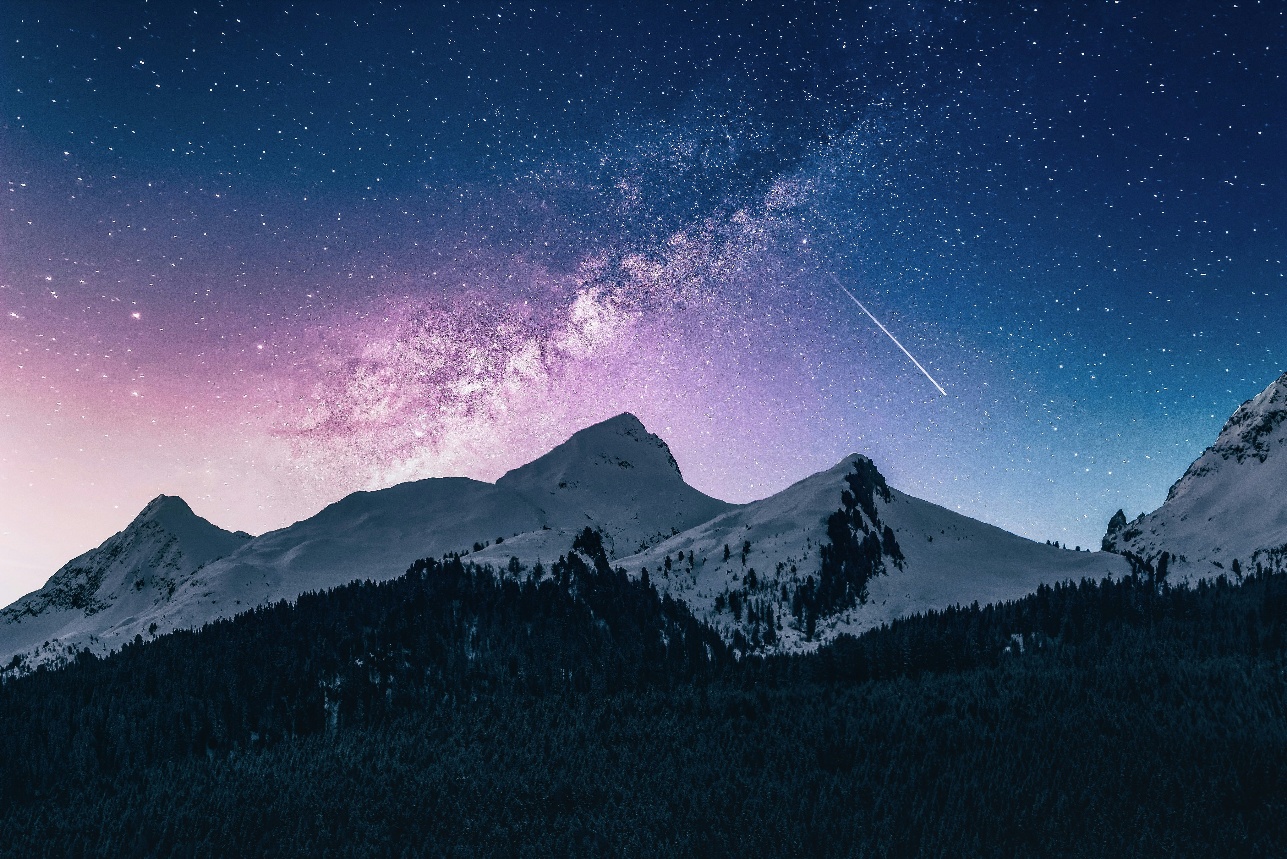 A star-filled sky above snowy mountains